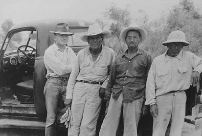 Four men stand in front of a truck in an early Landmark photo